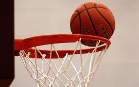 Basketball sitting on rim of basket
