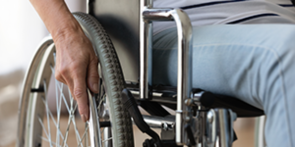 Up-close image of individual in a wheelchair with a focus on the wheel and seat area