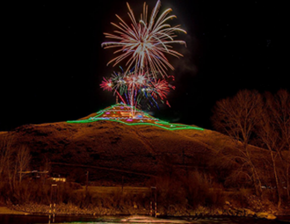 Tenderfoot Mountain with Christmas tree-outlined lights and fireworks exploding above