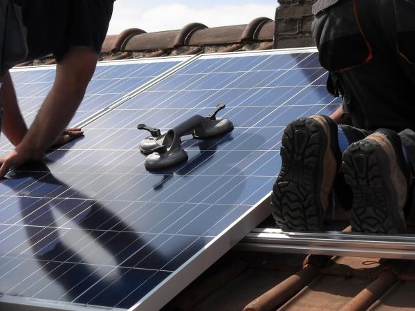 Solar panel installation on a residential roof with two workers