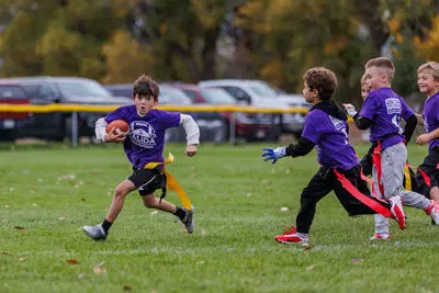 Salida Youth flag football participant running with a football