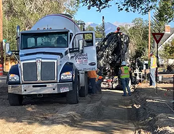 Several Public Works employees working alongside a paving truck in Salida